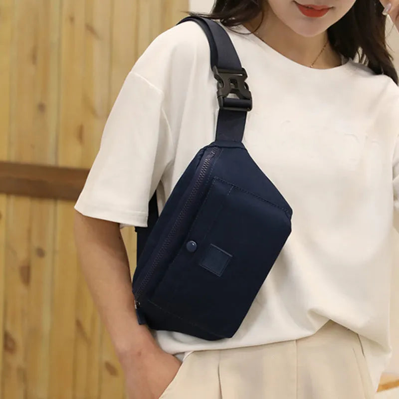 Women's nylon crossbody fanny pack in black with zippered compartments and letter detail.