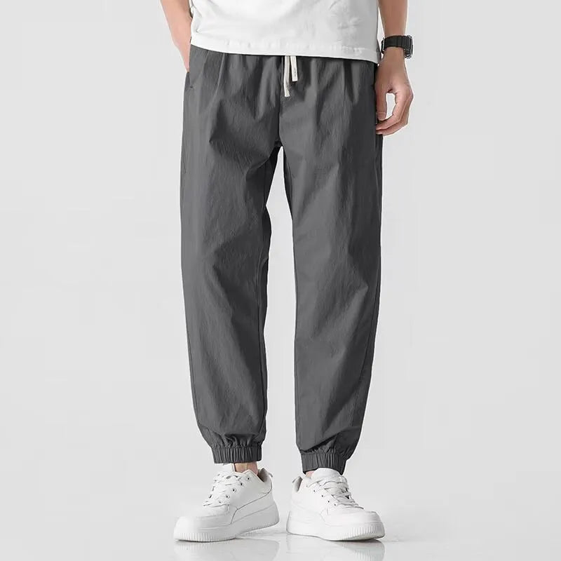 Men's loose cuffed cargo pants in black polyester fabric with cuffed hem and relaxed fit