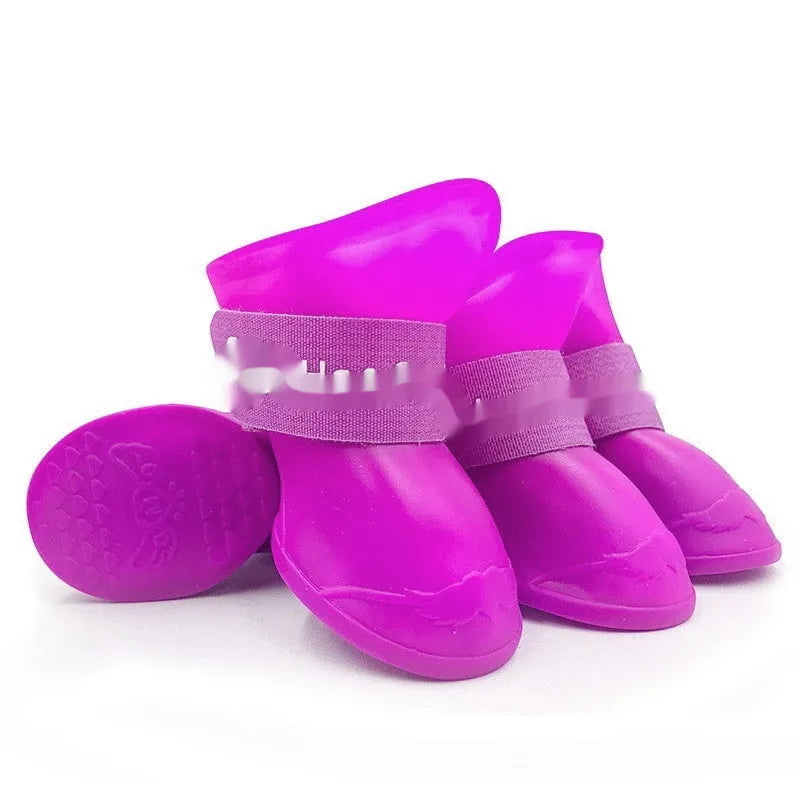 Set of four soft-soled rubber pet rain shoes in assorted colours on a grey background.