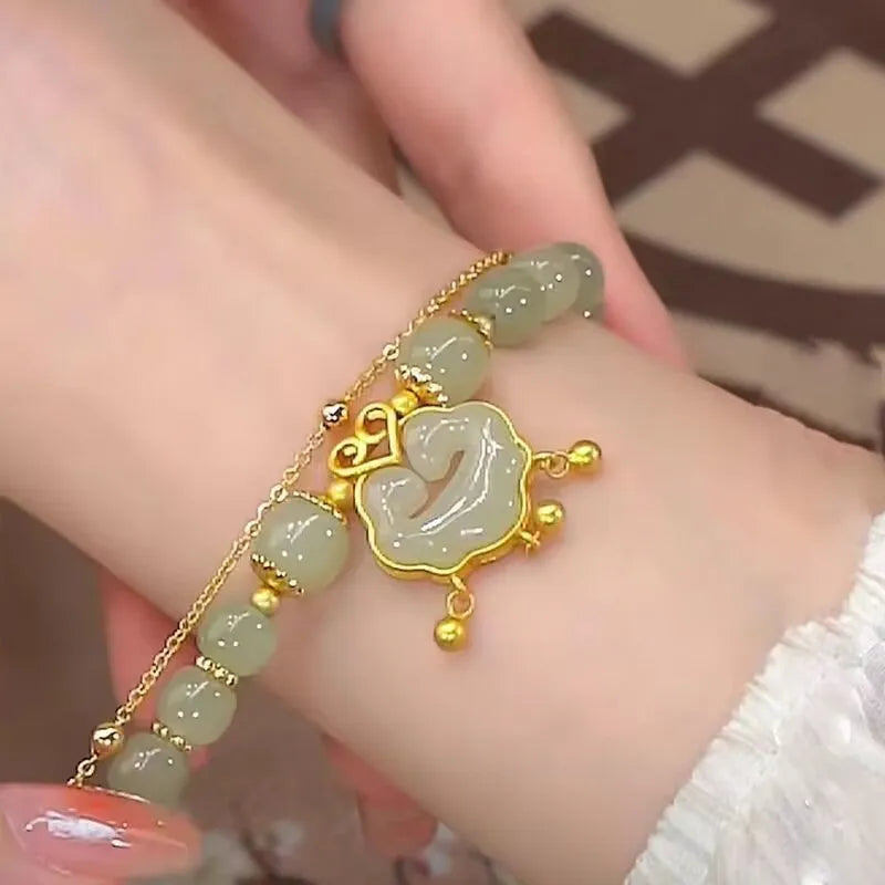 Close-up of a women's green double-layer bracelet with a drop-shaped Xiangyun safety lock pendant.