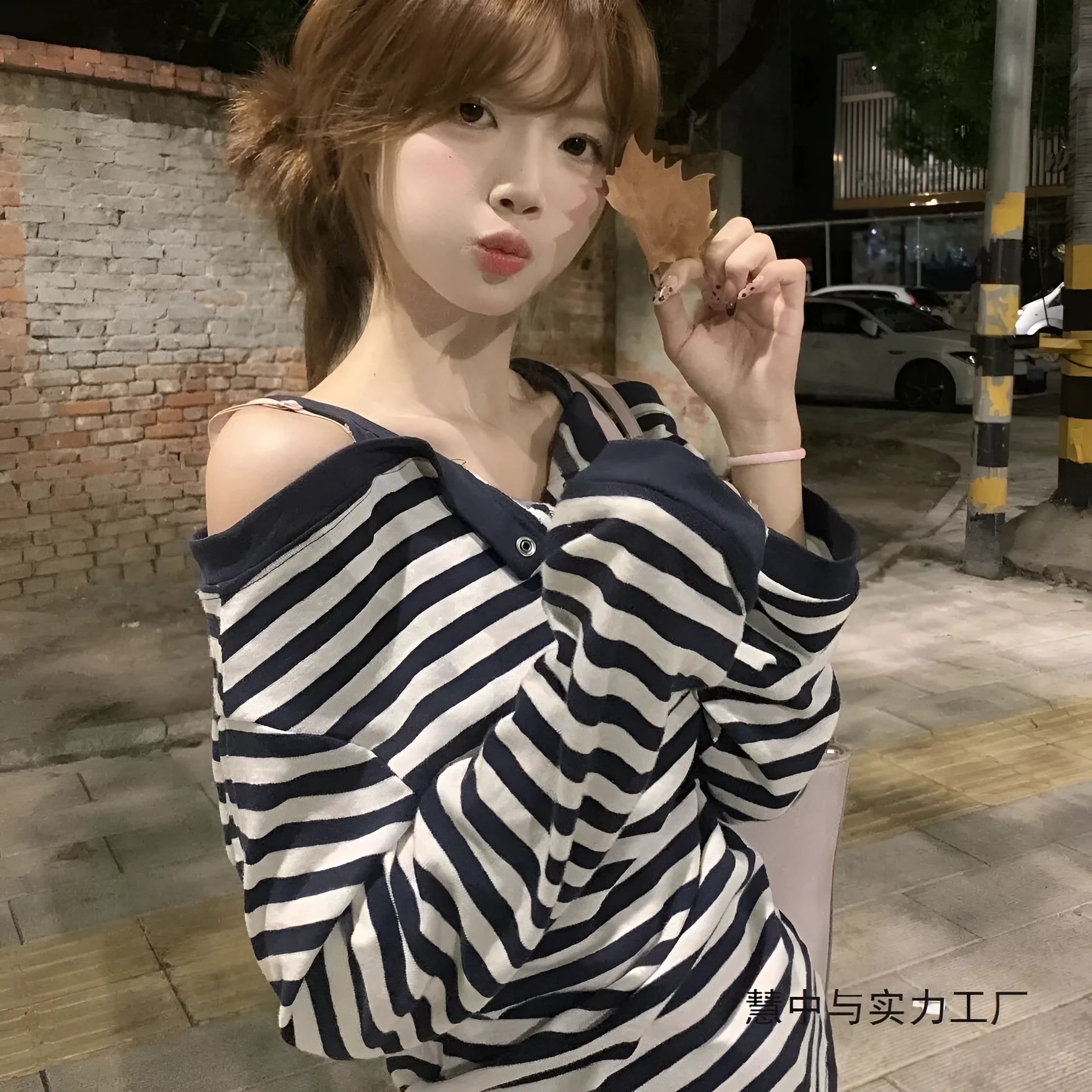 Dark blue oversized women's long-sleeved t-shirt with embroidery, stripes, and button detail on a hanger.