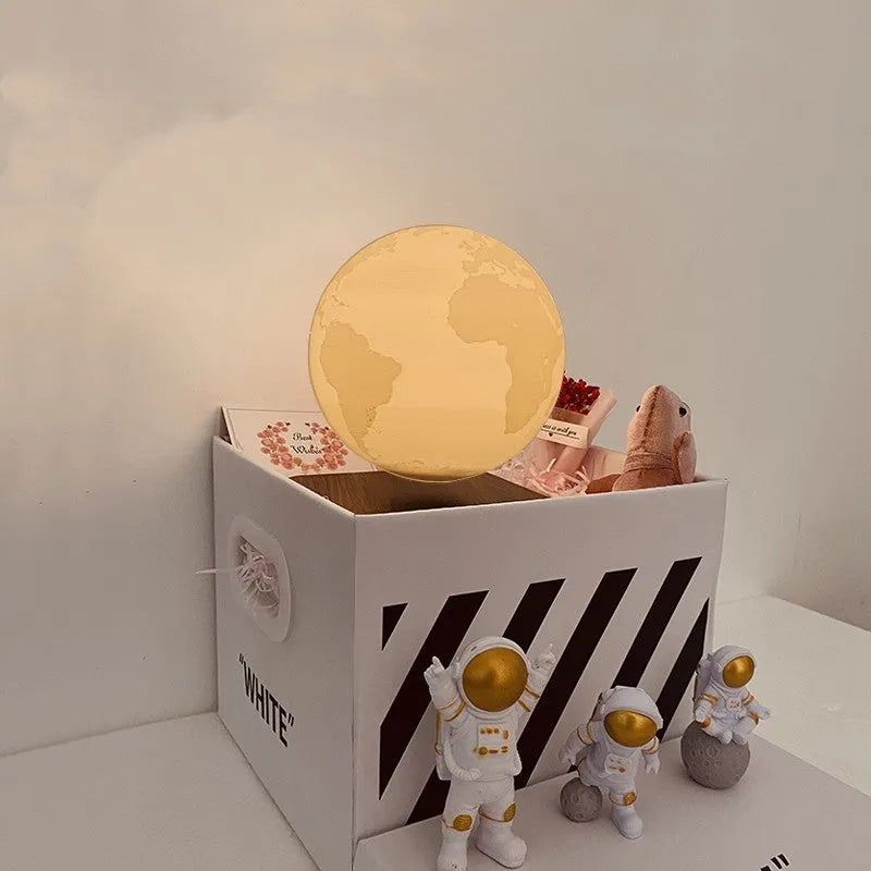 Moon planet floating LED night light with three astronaut figurines on dark surface