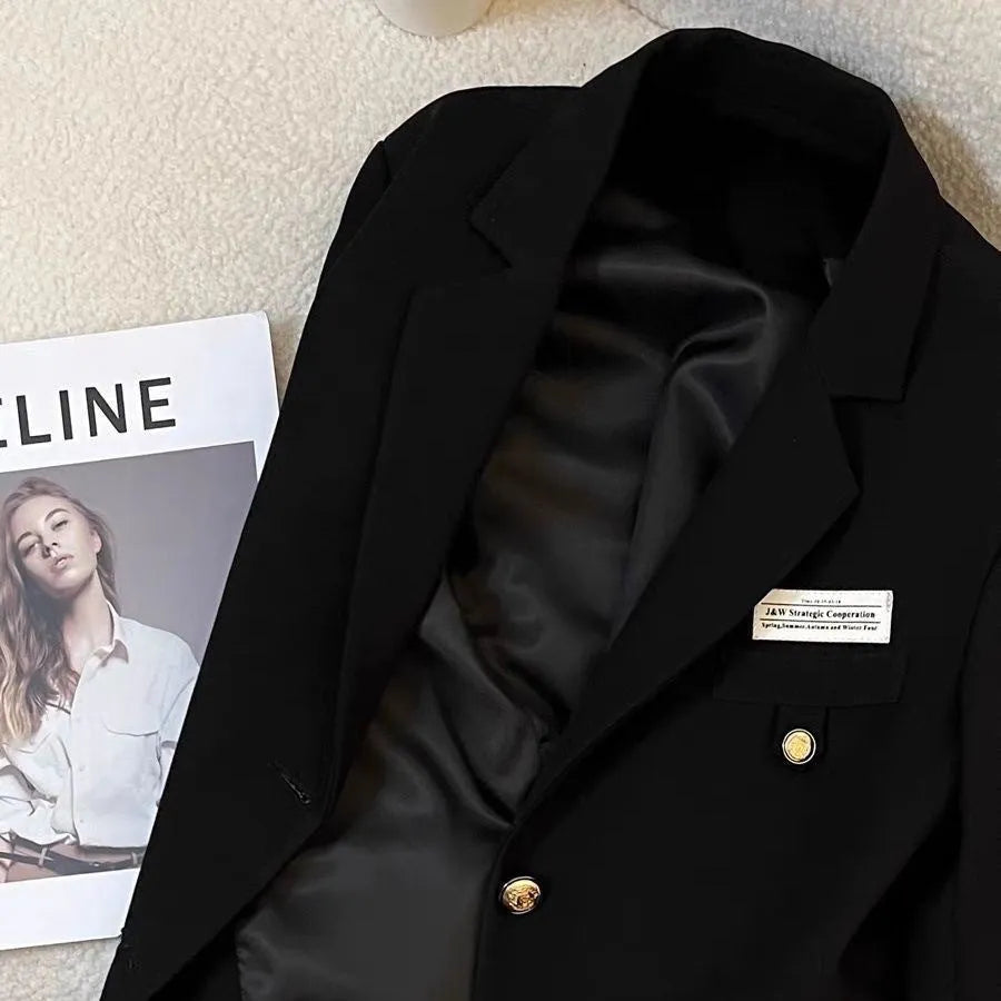 Women's black loose-fit short suit coat with pockets, shown on a hanger.