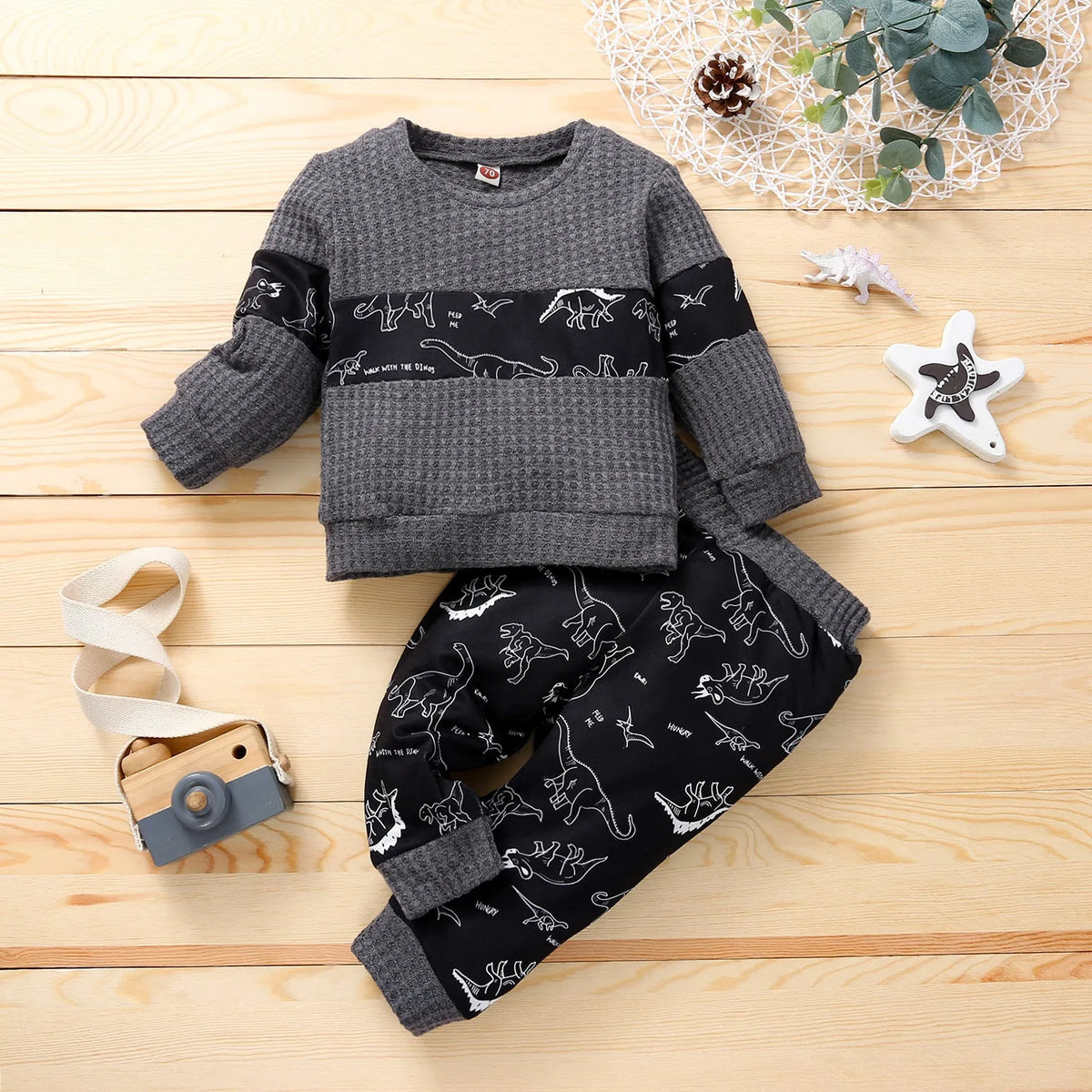 Cotton children's pants suit with dinosaur cartoon pattern in beige, pullover top and trousers set on child model