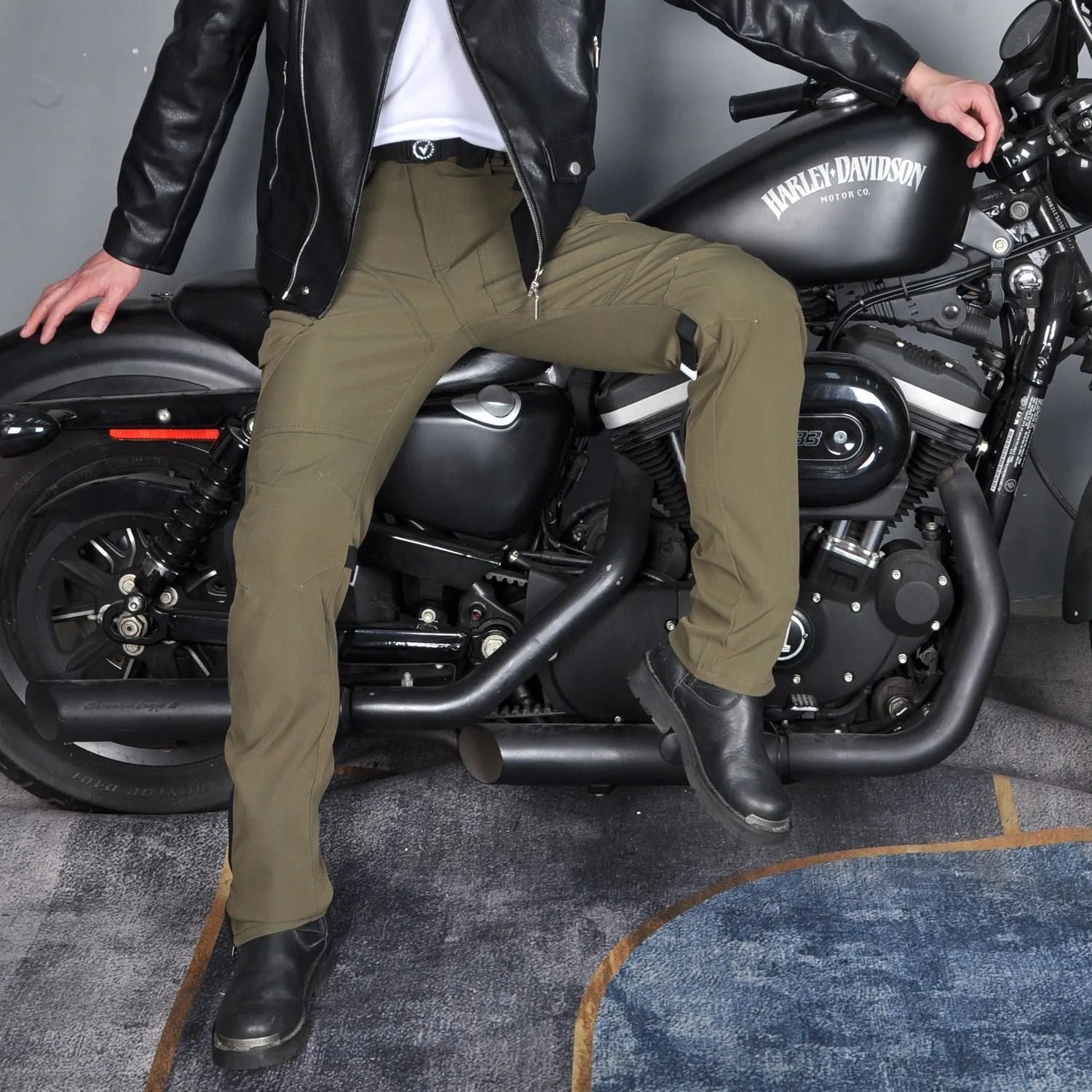 Men's green waterproof motorcycle cycling trousers with belt and protective gear on hanger.