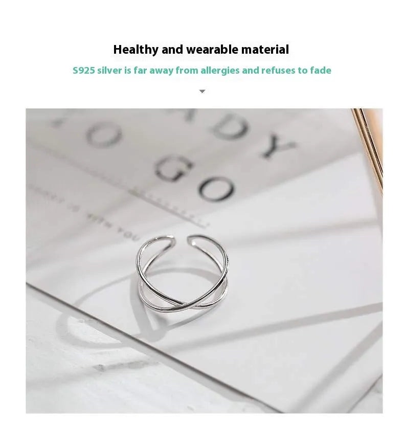 Silver plated geometric cross ring with adjustable opening on a plain background