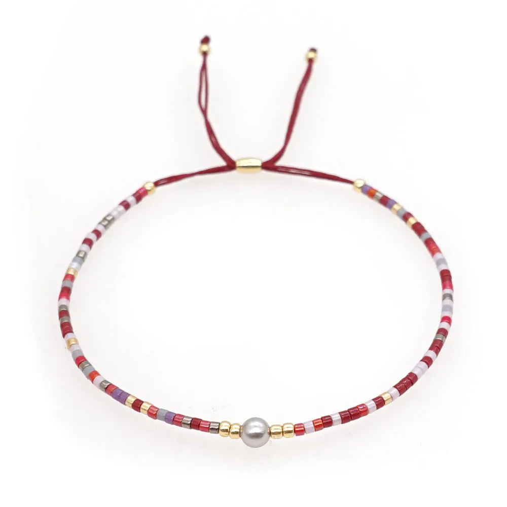 Close-up of a handmade women's bracelet with colourful glass and semi-precious stone geometric beads on a black stretch cord.