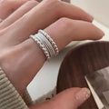 Copper-coloured geometric alloy ring with woven twisted texture and adjustable band.