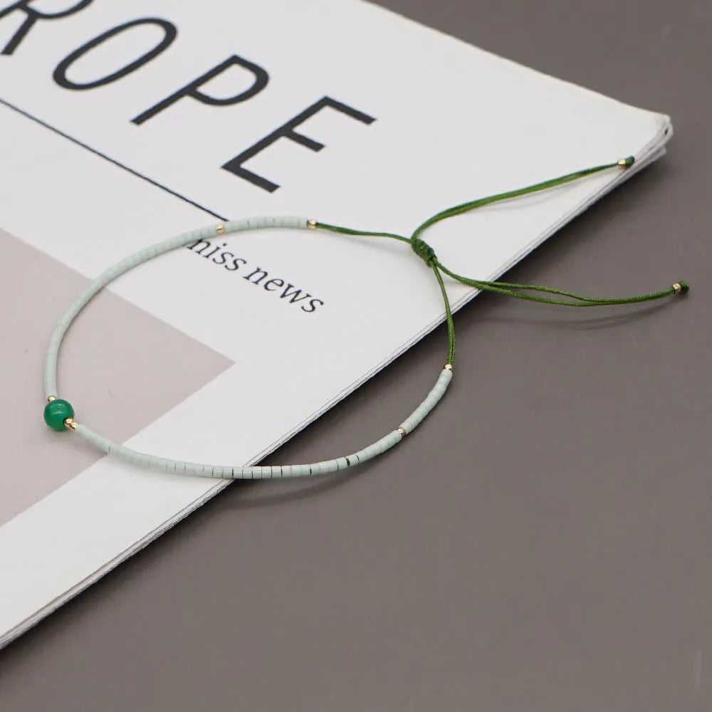 Close-up of a handmade women's bracelet with colourful glass and semi-precious stone geometric beads on a black stretch cord.
