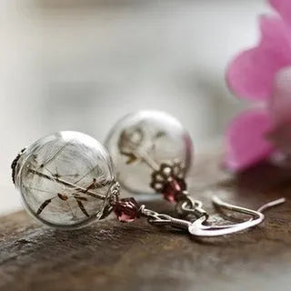 Transparent glass ball earrings with a dandelion seed inside, on a silver French hook.