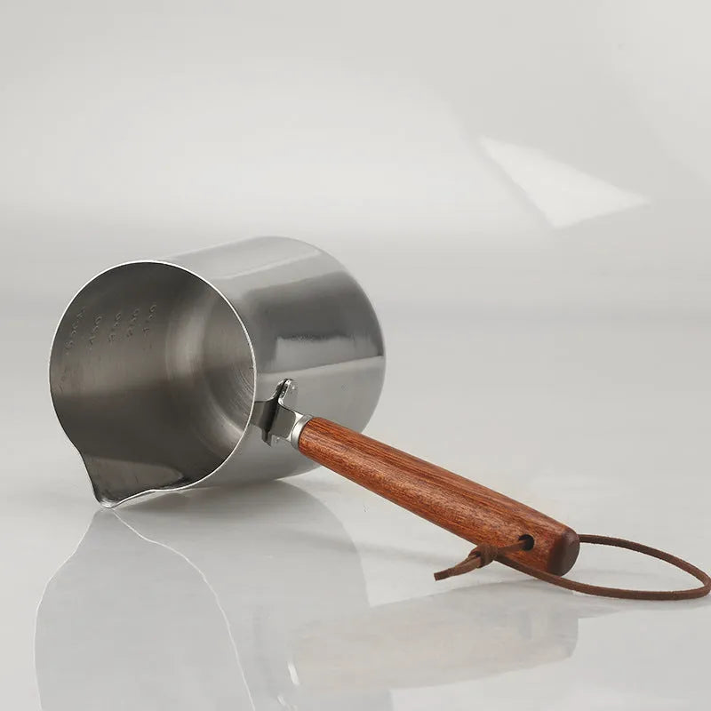 Stainless steel latte art milk cup with wooden handle and interior measuring scale