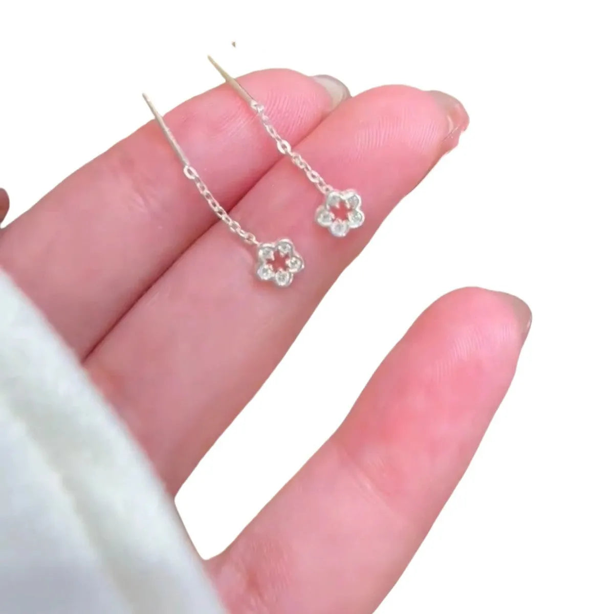 Silver hollow flower hanging earrings with detailed petal design and needle silver construction