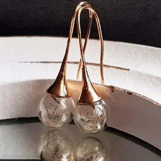 Transparent glass ball earrings with a dandelion seed inside, on a silver French hook.