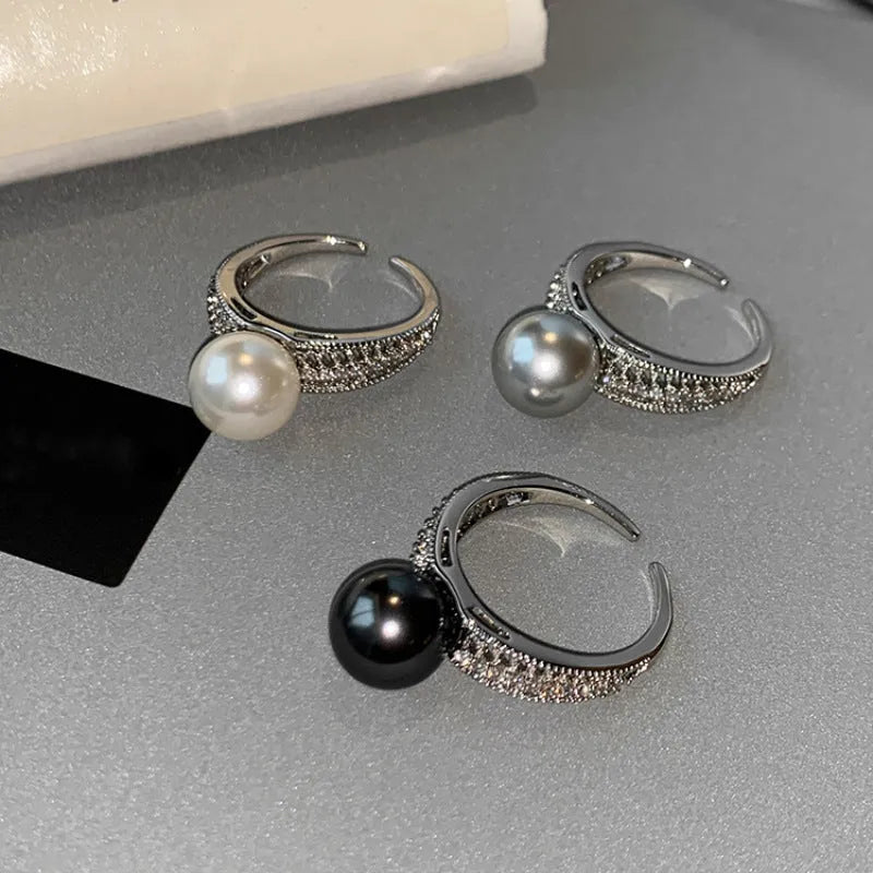 Adjustable open copper ring with a black pearl in a geometric shape for women, shown on an index finger.