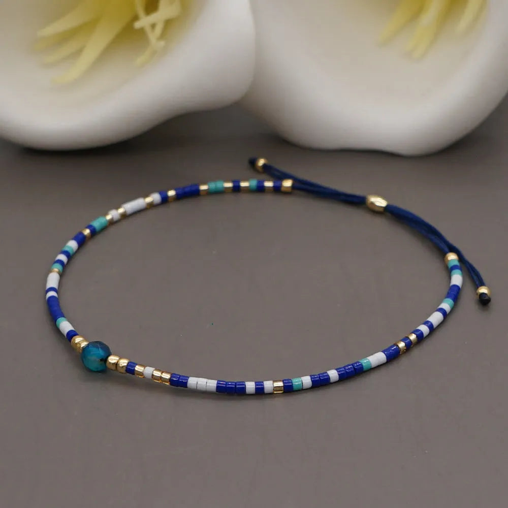 Close-up of a handmade women's bracelet with colourful glass and semi-precious stone geometric beads on a black stretch cord.