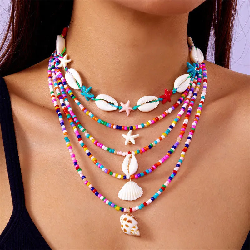 Five women's fashion necklaces with starfish and shell bead designs in blue and multicolour options