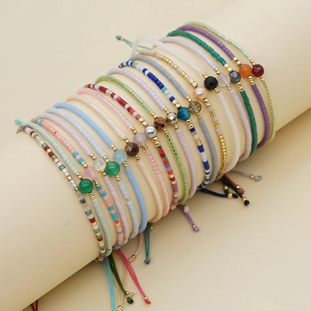 Close-up of a handmade women's bracelet with colourful glass and semi-precious stone geometric beads on a black stretch cord.