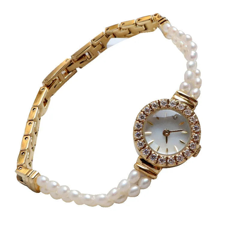 Women's light gold bracelet watch with freshwater pearls and a small round dial.