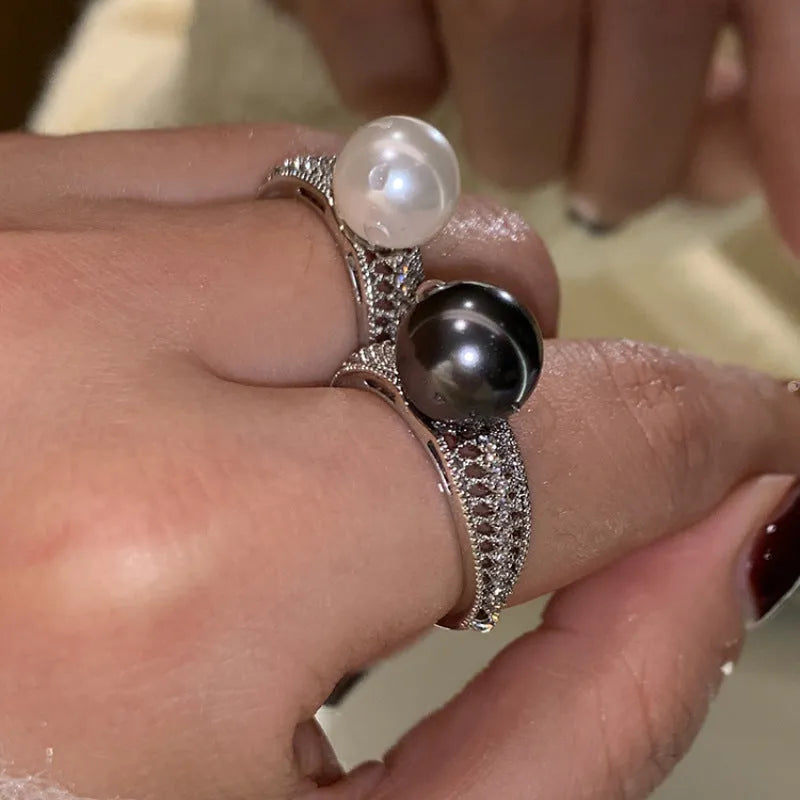 Adjustable open copper ring with a black pearl in a geometric shape for women, shown on an index finger.