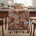 Beige jacquard fabric table runner with floral pattern and long tassels laid flat on a table.