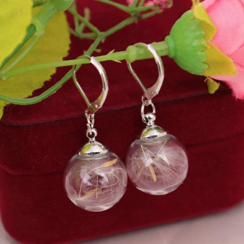 Transparent glass ball earrings with a dandelion seed inside, on a silver French hook.