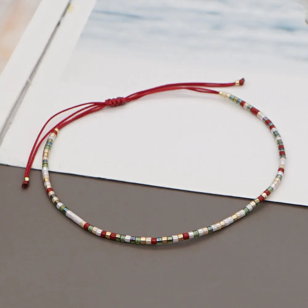 Close-up of a handmade women's bracelet with colourful glass and semi-precious stone geometric beads on a black stretch cord.