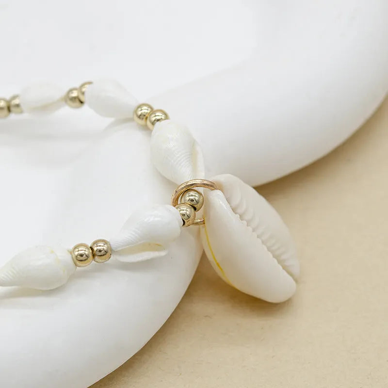 White bead necklace with a mother of pearl conch shell pendant on a regular chain.