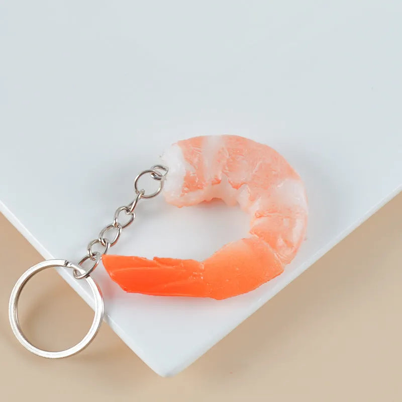White PVC shrimp simulation keychain with metal door buckle, shown from the side to highlight its 1.5cm thickness.
