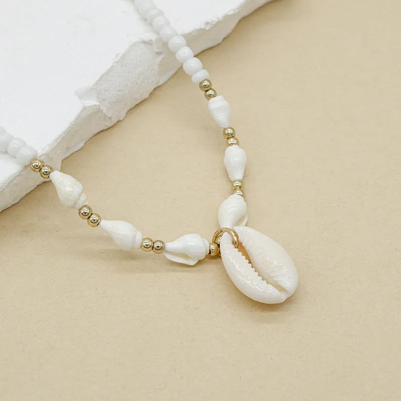 White bead necklace with a mother of pearl conch shell pendant on a regular chain.