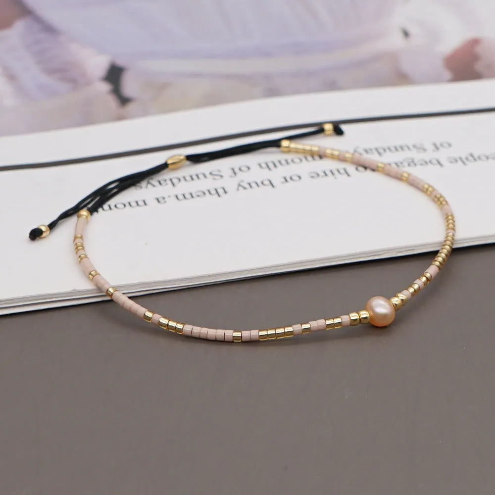 Close-up of a handmade women's bracelet with colourful glass and semi-precious stone geometric beads on a black stretch cord.