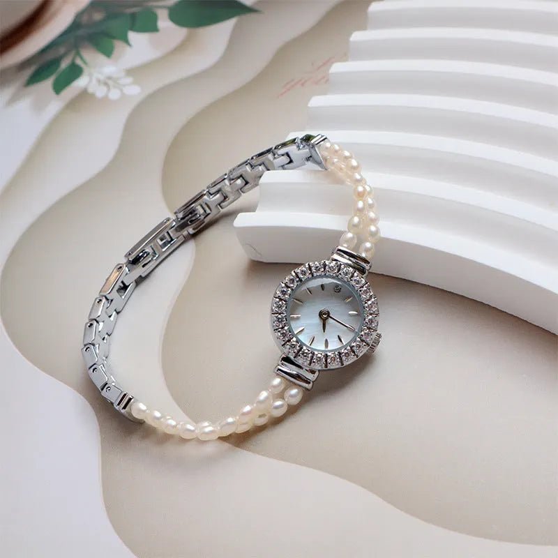 Women's light gold bracelet watch with freshwater pearls and a small round dial.