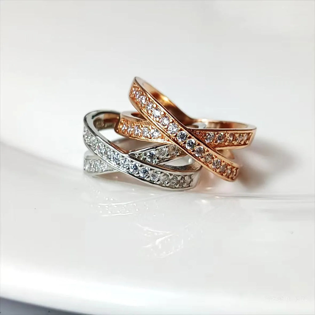 Metal ring with cross design and zircon detail in silver or rose gold finish.