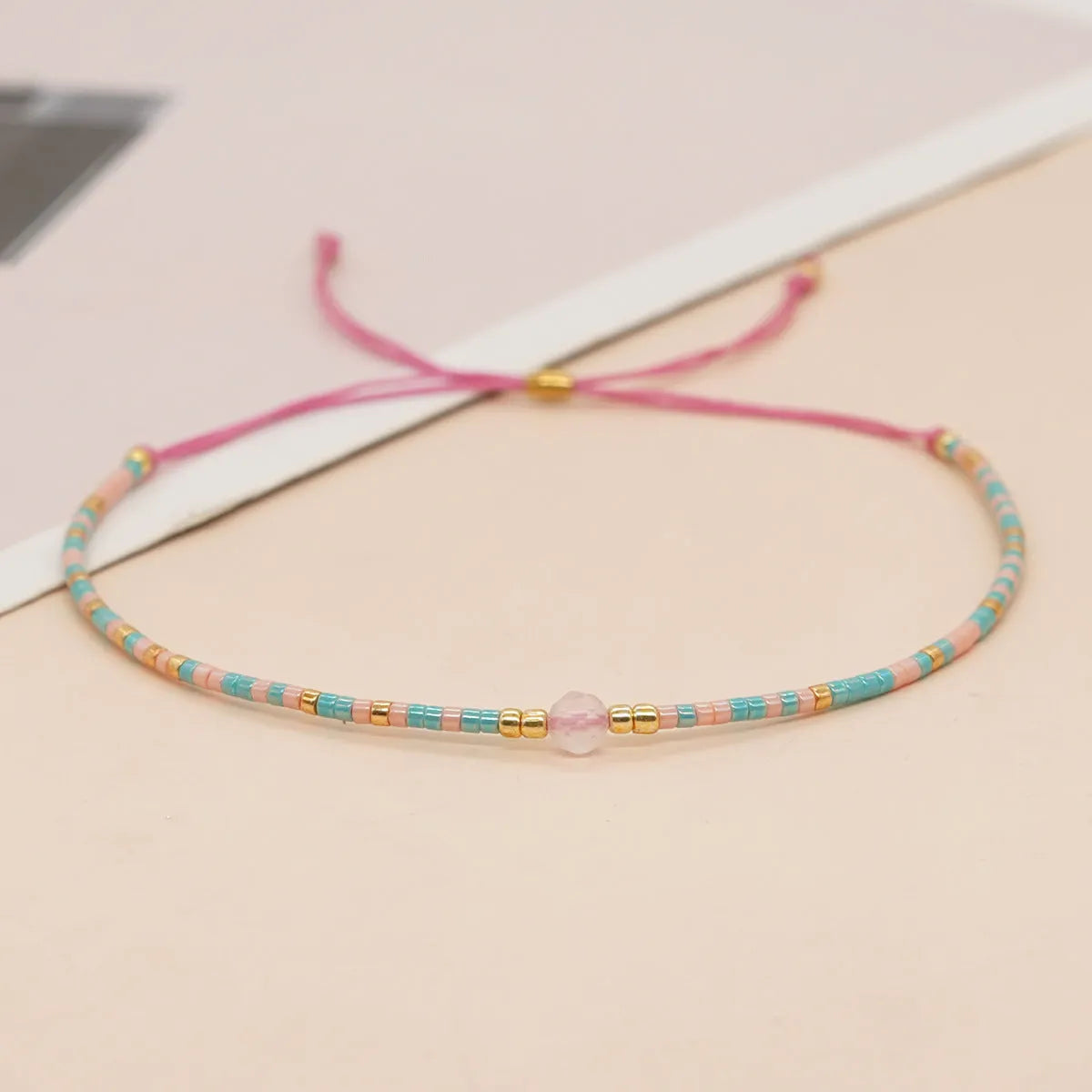 Close-up of a handmade women's bracelet with colourful glass and semi-precious stone geometric beads on a black stretch cord.