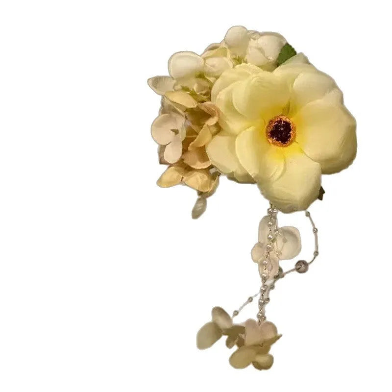 A handmade hair clip with a flower and tassel design in either yellow or purple.