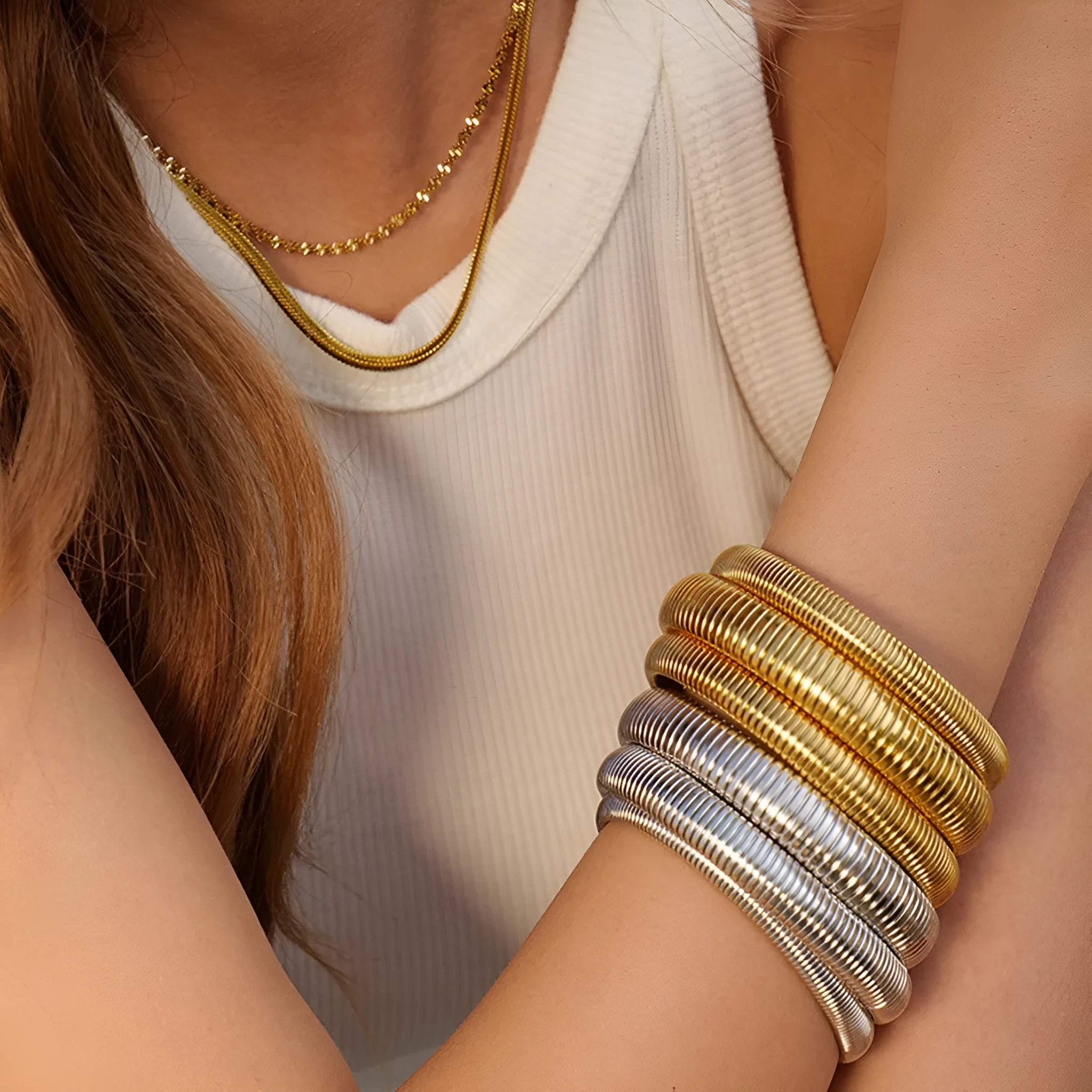 Women's titanium steel bracelet with vertical stripes, shown in gold and silver colours with ring elastic closure.