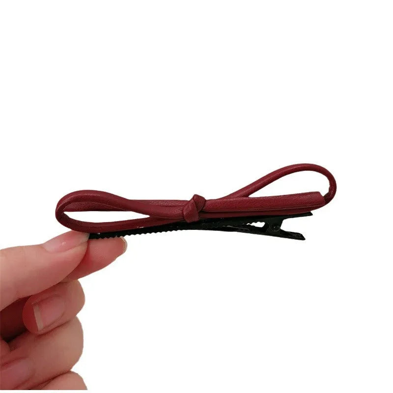 Wine red leather bow design hair barrettes on a white background.