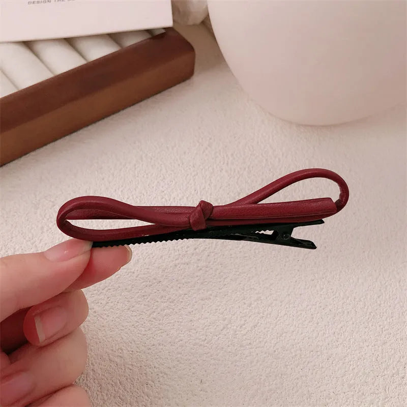 Wine red leather bow design hair barrettes on a white background.