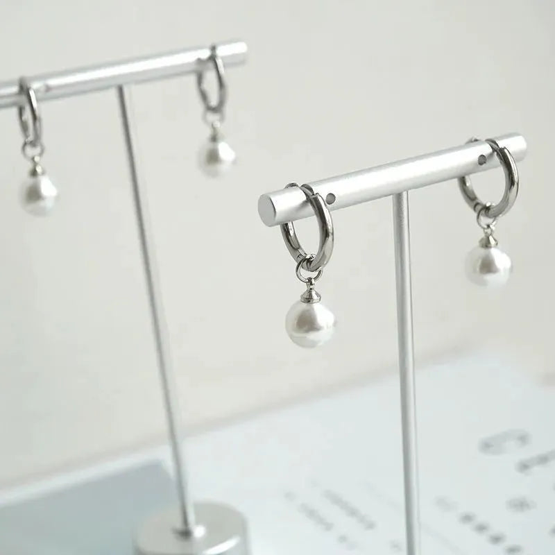 A pair of women's geometric alloy drop earrings with pearl finish and titanium steel posts.