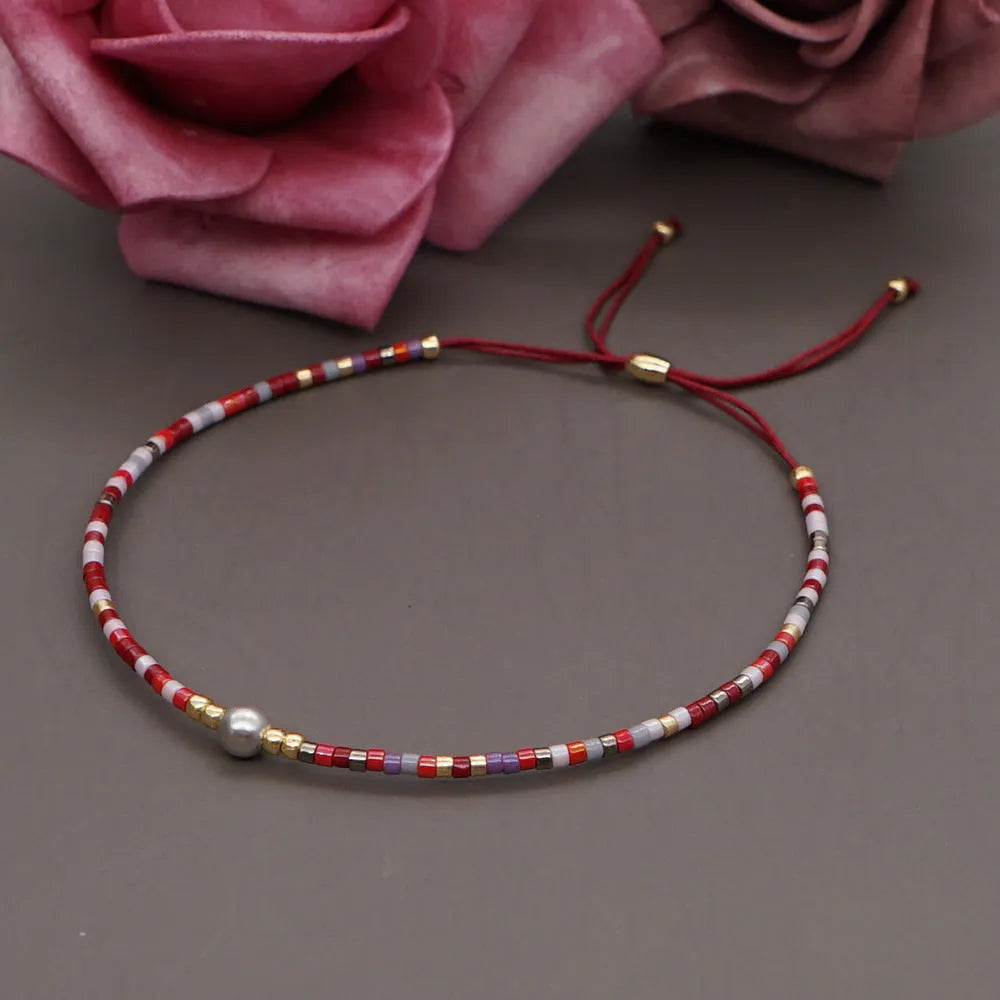 Close-up of a handmade women's bracelet with colourful glass and semi-precious stone geometric beads on a black stretch cord.