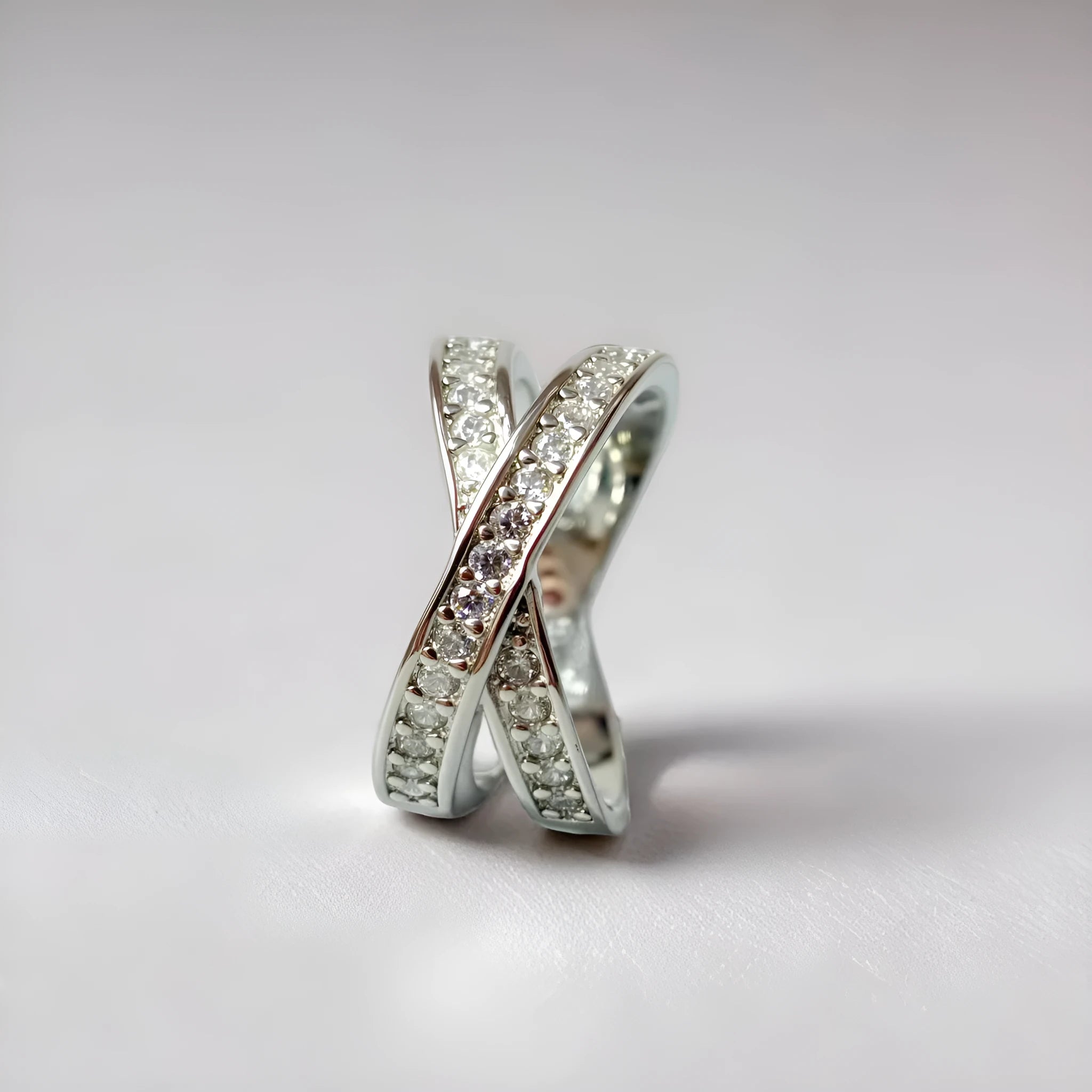 Metal ring with cross design and zircon detail in silver or rose gold finish.
