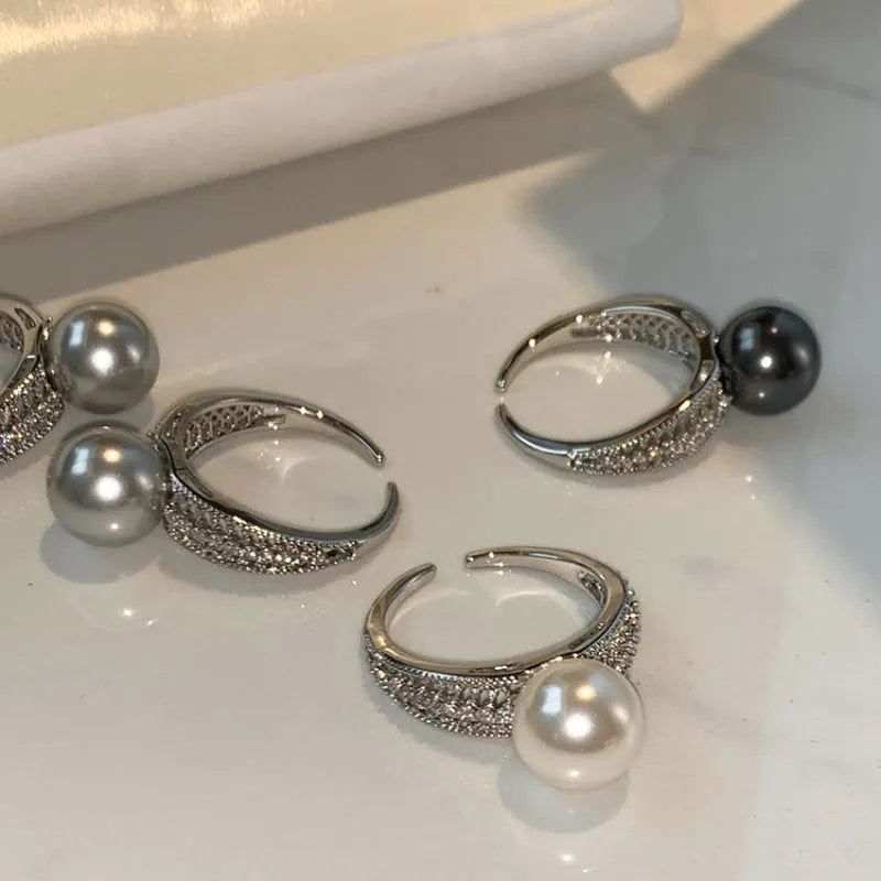 Adjustable open copper ring with a black pearl in a geometric shape for women, shown on an index finger.