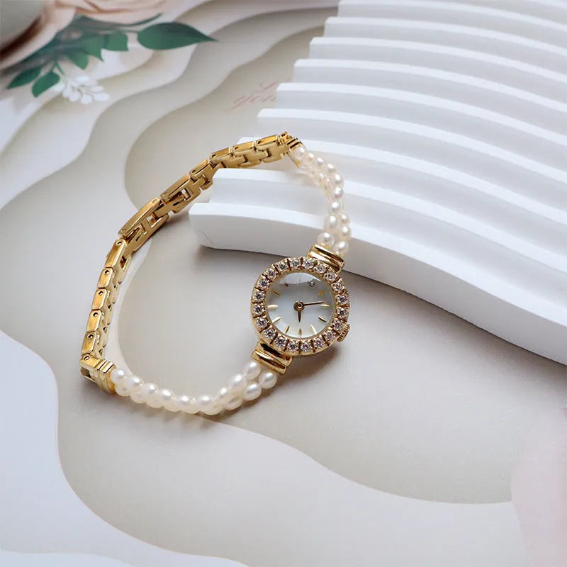 Women's light gold bracelet watch with freshwater pearls and a small round dial.