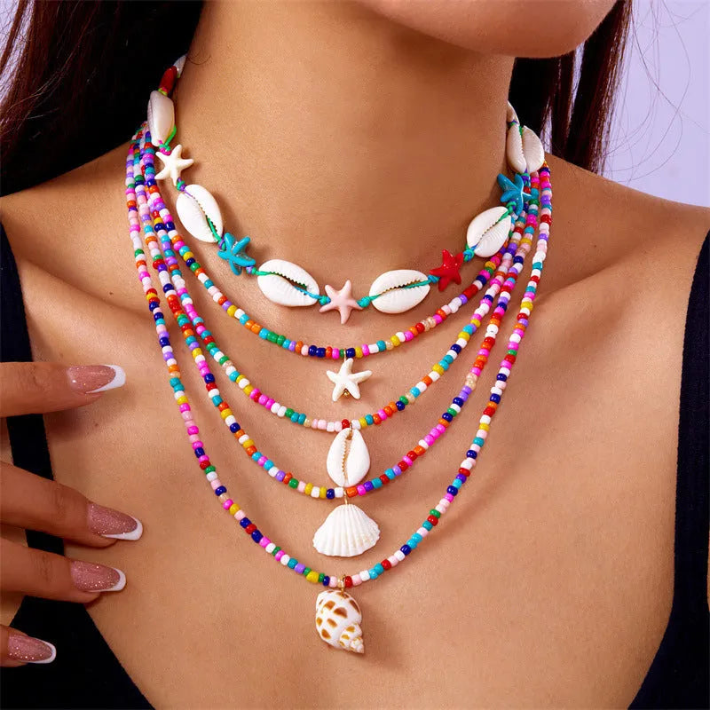 Five women's fashion necklaces with starfish and shell bead designs in blue and multicolour options