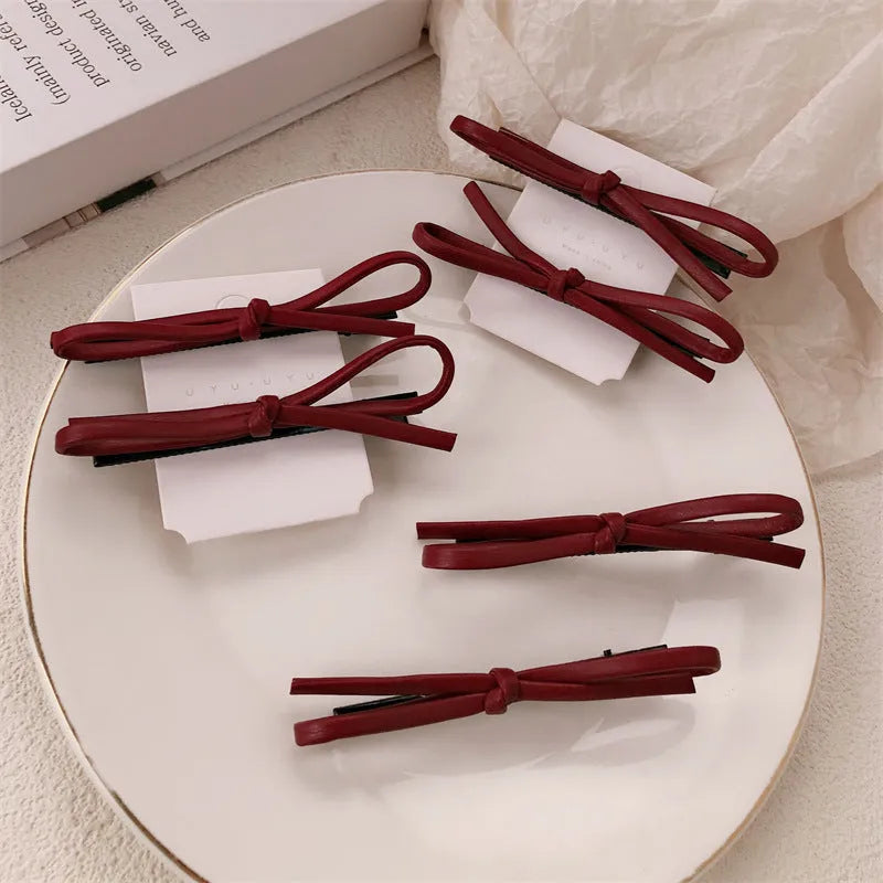 Wine red leather bow design hair barrettes on a white background.
