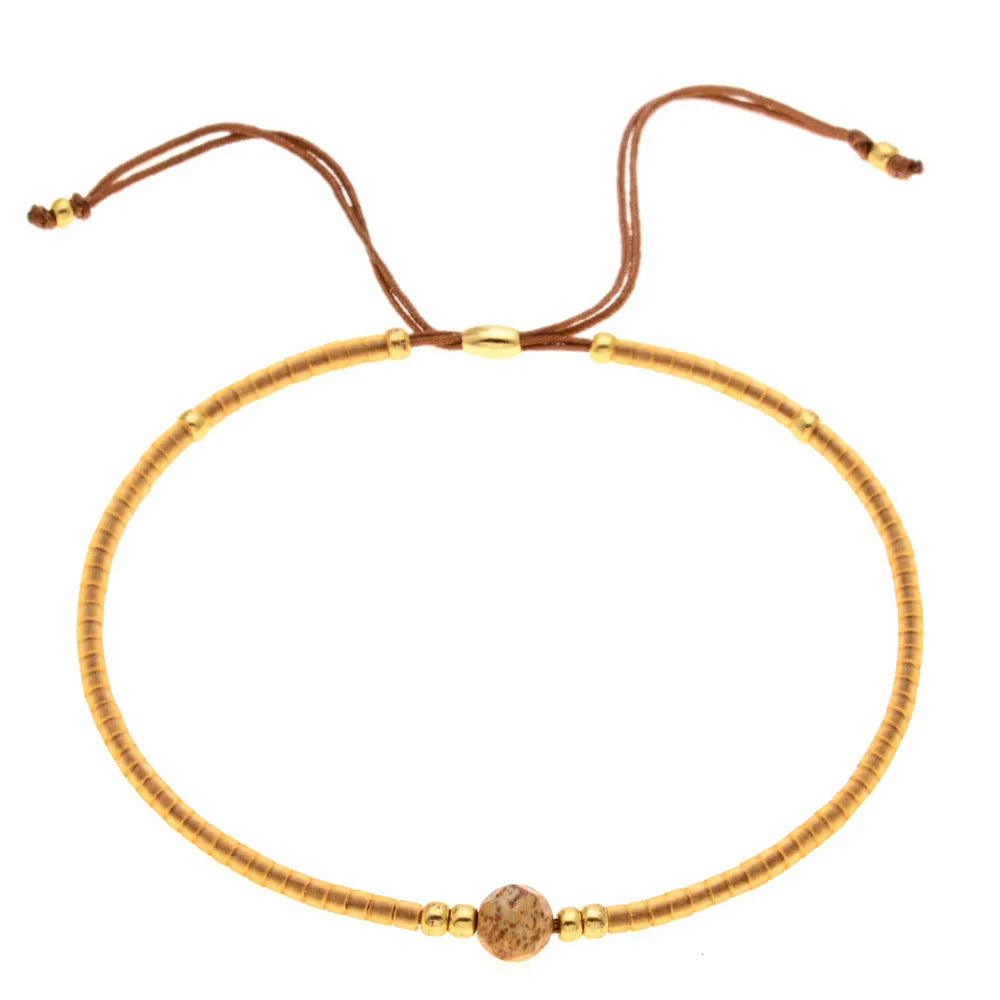 Close-up of a handmade women's bracelet with colourful glass and semi-precious stone geometric beads on a black stretch cord.