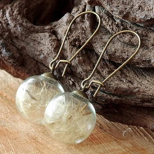 Transparent glass ball earrings with a dandelion seed inside, on a silver French hook.