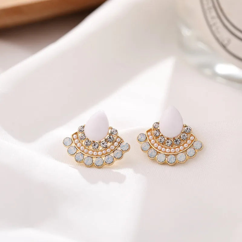 Silver retro fan-shaped stud earrings with rhinestone and opal details on a grey background.