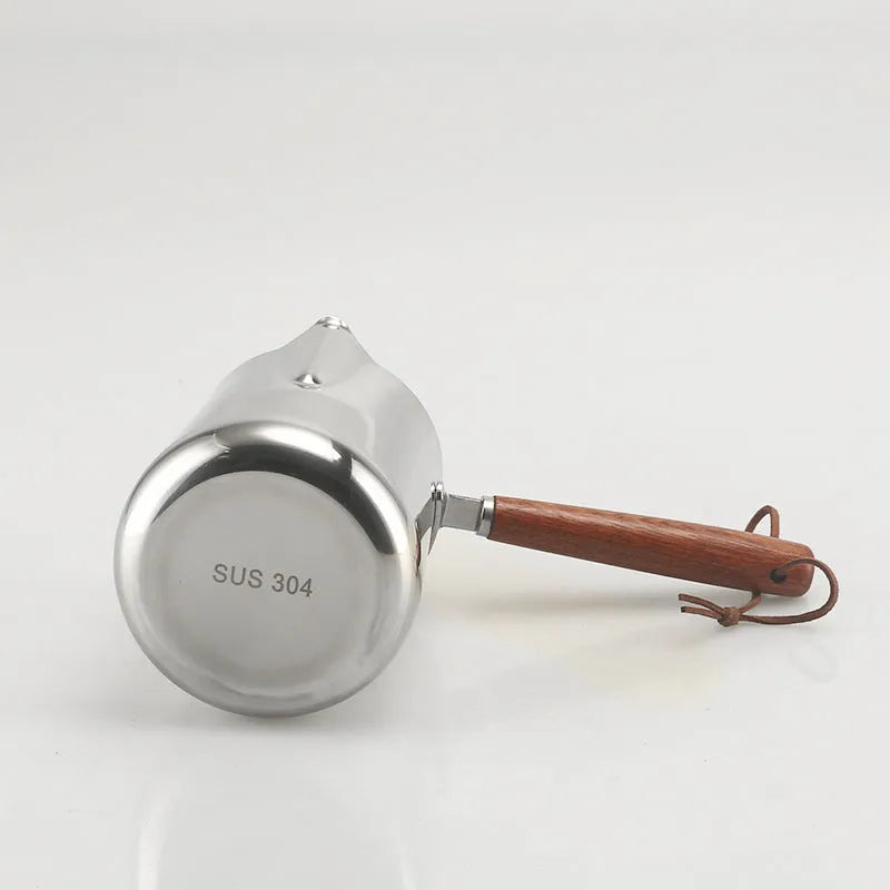 Stainless steel latte art milk cup with wooden handle and interior measuring scale