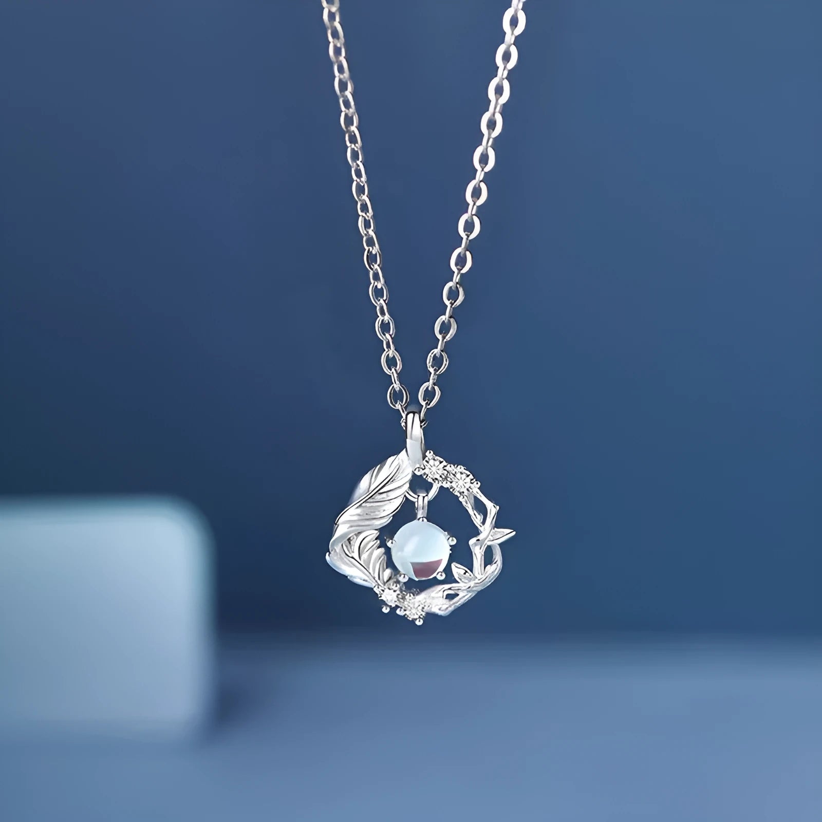 Geometric tree and bird pendant necklace for women with an adjustable chain in a blue eucalyptus colour.