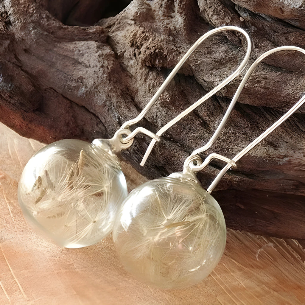 Transparent glass ball earrings with a dandelion seed inside, on a silver French hook.
